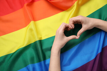 Woman making heart with her hands on LGBT flag