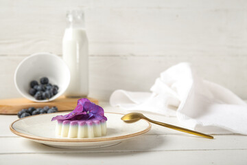 Plate of panna cotta with blueberry and beautiful hydrangea flowers on white wooden table