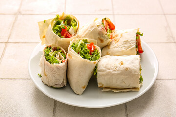 Plate of tasty lavash rolls with tomatoes and greens on white tile background