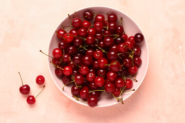 Bowl with red sweet cherries on pink background