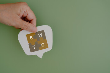 hand hold real white speech bubble paper cut with SWOT, for Strengths, Weaknesses, Opportunities, Threats, text with green background