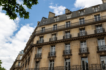 Obraz premium Apartment Building Facade with Balconies and Windows Under Cloudy Sky