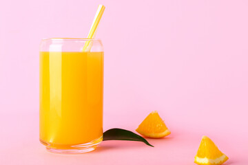 Glass of fresh orange juice and leaf on pink background
