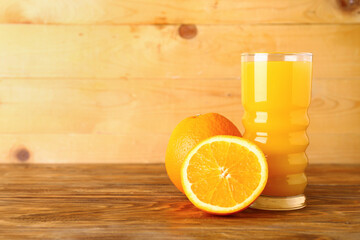 Glass of fresh orange juice on wooden background