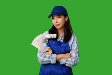 Female Asian painter with paint color palettes and roller on green background