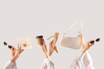 Female hands with stylish women's bags, high heels, sunglasses and cup of coffee on grey background