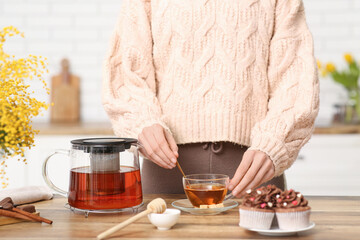 Young woman stirring black tea in kitchen