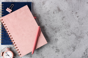 Composition with notebooks, clock, pen and binder clips on grey background