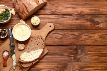 Board of bread slices with different spices and bowls of fresh butter on wooden background