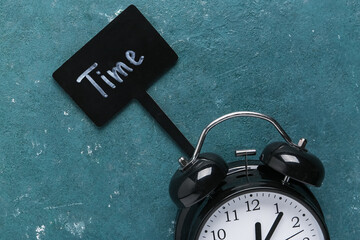 Word TIME and alarm clock on green background. Time management concept. Closeup