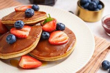 Tasty pancakes with blueberries and strawberry on white background