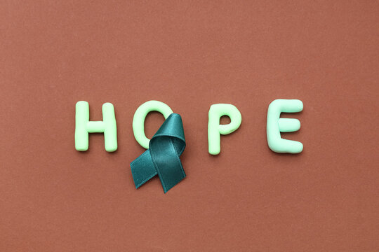 Teal ribbon and word HOPE on brown background. Sexual Assault Awareness Month