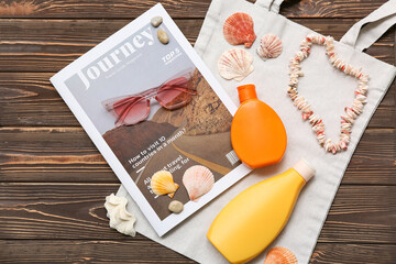 Bottles of sun protection cream, magazine, seashells, sunglasses and bag on wooden background
