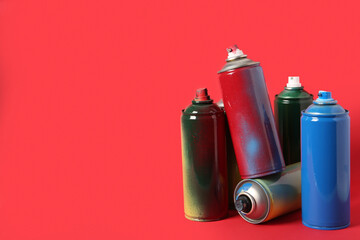 Many spray paint cans on red background