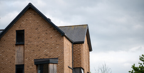 Gable rooftop on modern brick house with single window and angular architectural detail
