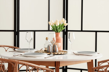 Table setting with tulips near folding screen in room
