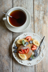 Light breakfast, pancakes with fruits and berries on the table.