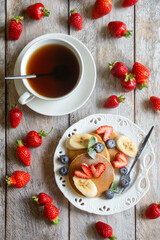 Light breakfast, pancakes with fruits and berries on the table.
