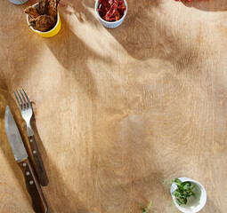 Wooden background with scattered spices and herbs, bright natural lighting, overhead composition