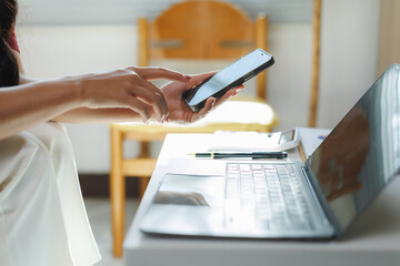 Businesswoman using smartphone and laptop in home office