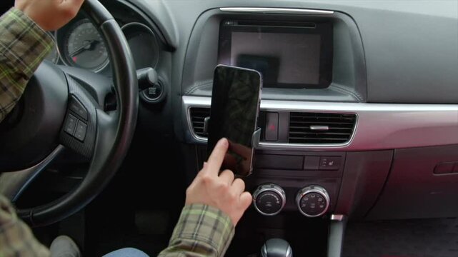 Close-up of African American female driver sitting in car, searching for travel route on smartphone using modern GPS navigation app while driving vehicle on road trip.