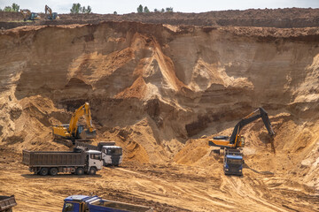 The process of loading sand in a sand quarry. Trucks are waiting for cargo.