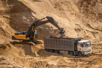 The process of loading sand in a sand quarry. Trucks are waiting for cargo.