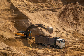 The process of loading sand in a sand quarry. Trucks are waiting for cargo.