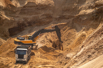 The process of loading sand in a sand quarry. Trucks are waiting for cargo.