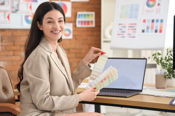 Beautiful designer with color palettes at table in office