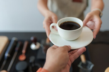 Barista serving a cup of freshly brewed coffee to customer