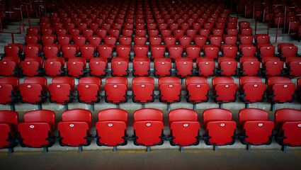 Rows of empty red stadium seats in a curved arrangement, creating a sense of anticipation and vastness in the venue. AI generated.
