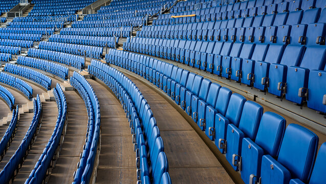 Rows of empty blue stadium seats in a curved arrangement, creating a sense of anticipation and vastness in the venue. AI generated.
