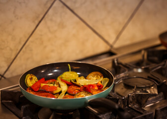 Colorful grilled vegetables cooking in a frying pan on a gas stove in a professional kitchen,...