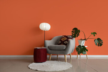 Interior of living room with grey armchair, lamp and Monstera plant
