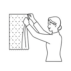 Woman hanging a fabric with a stitched pattern on a wall with cheerful expression.