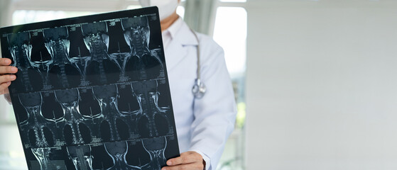 Orthopedist checkup cervical spine x-ray film and diagnose cervical spondylosis at doctor room with copy spacewide view.