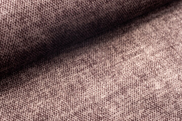 A twisted piece of brown fabric. A roll of red fabric. Textile. Folds.