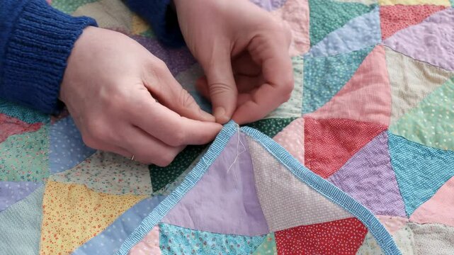 Hands holding a patchwork quilt with colorful fabrics