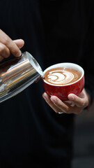 Barista Hand Pouring Latte Art into Coffee Cup – Close-up Potrait Coffee Making Process