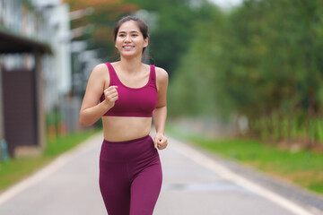 Fototapeta premium Smiling asian sportswoman running outside in sportswear