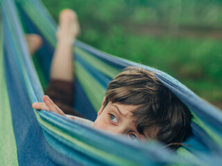 Young Boy Peeking from Hammock in Garden