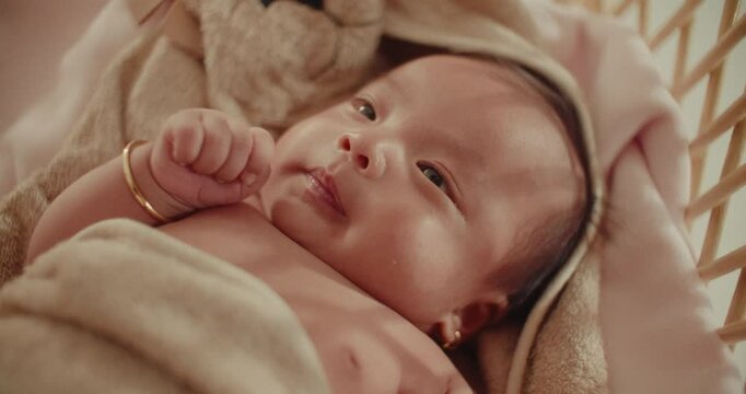 Gentle Focus Transition on Newborn in Towel resting peacefully smiling on wooden cradle natural warm light , family happy moment