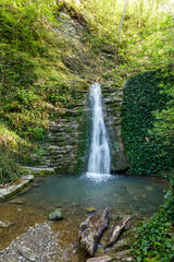 A waterfall is flowing into a small pool of water