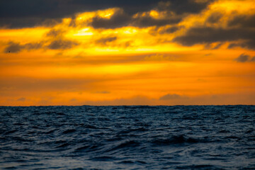 A breathtaking and stunning view of the vast ocean at sunset, showcasing vibrant, rich hues of...