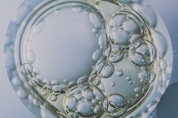 A macro image of oil and water bubbles over a sponge-like surface with soft gradients. The abstract composition evokes themes of skincare, moisture, and organic texture