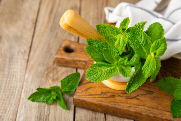 Fresh mint with mortar and pestle on wooden background. Melissa leaves. Healing herbs green mint...