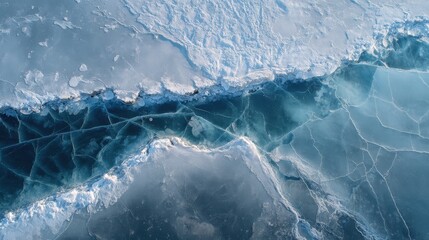 Aerial view of frozen lake with ice cracks and snow-covered shore in winter