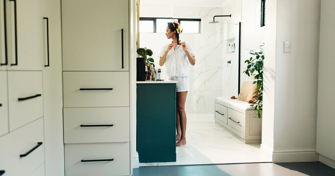 Home, woman and hair curlers in mirror for getting ready, morning routine or volume locks. Self care, person and happy in bathroom with haircare, pinup curls or beauty products for heatless hairstyle