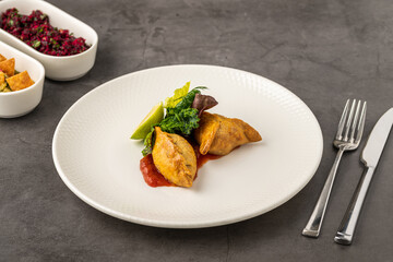 Meat empanadas on tomato sauce, served with fresh greens and lime wedge